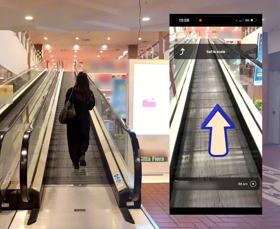 Visitor at Città Fiera following an AR route arrow in the phone browser up the escalator toward a store